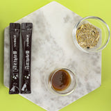 Oryginalne opakowanie produktu oraz mała szklanka wypełniona gęstym, ciemnym ekstraktem z korzenia dzwonka, gotowym do spożycia.